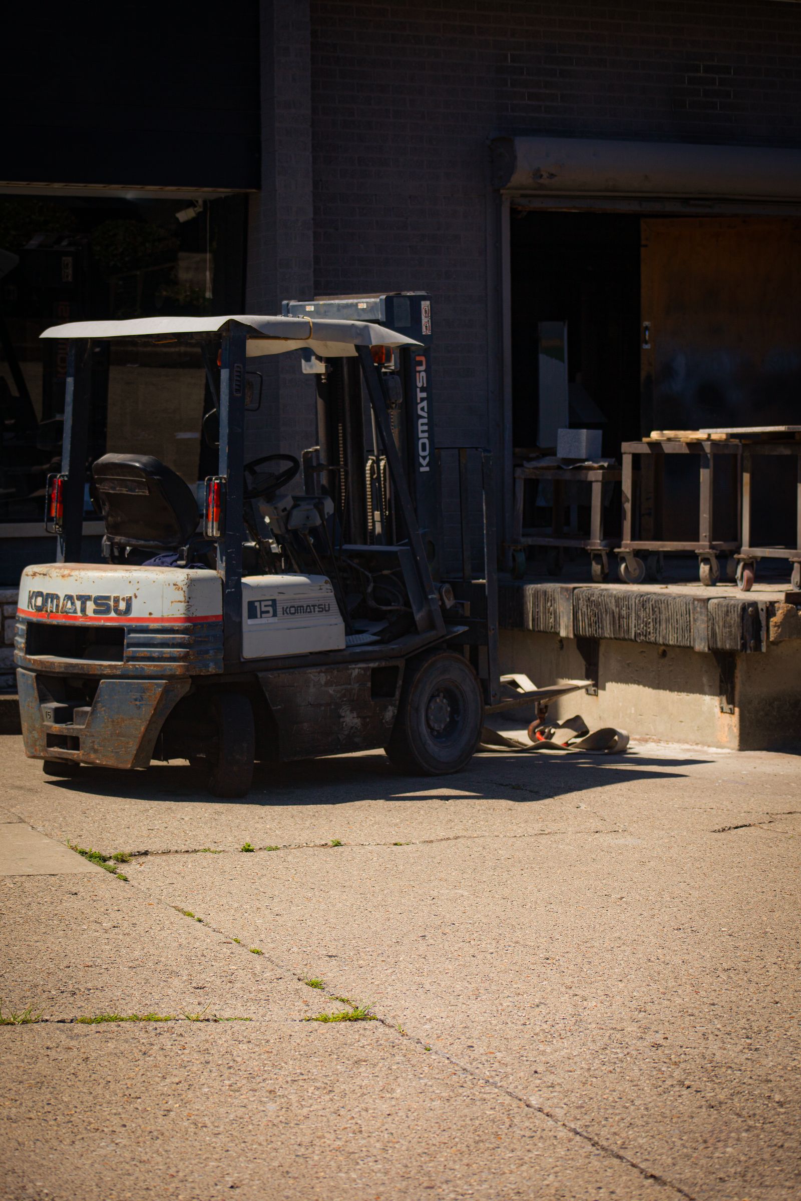 A forklift parked beside a raised warehouse loading dock in afternoon light.